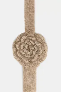Close-up macro view of a beige knitted flower detail on a soft winter headband.