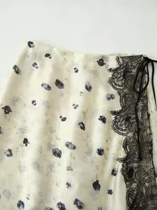 Dettaglio della gonna in raso stampato bianco panna con bordo in pizzo nero elegante.