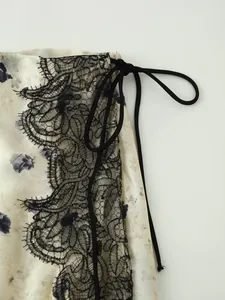 Dettaglio ravvicinato di pizzo nero e coulisse su tessuto di raso a fiori eleganti