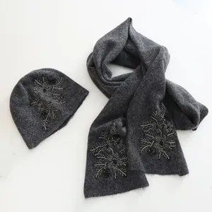 Detailed view of gray knitted hat and scarf set with elegant floral bead embroidery