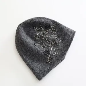 Close-up view of the intricate bead and sequin floral embroidery on a gray felt beanie