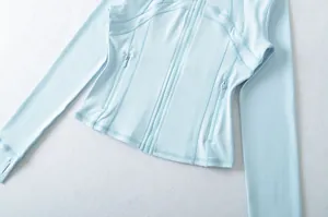 Dettaglio della giacca da yoga azzurra slim-fit con tasche a zip e asole per i pollici