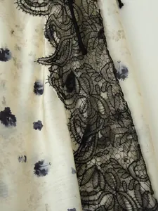 Dettaglio macro con ricamo in pizzo nero su elegante tessuto satinato a fiori.