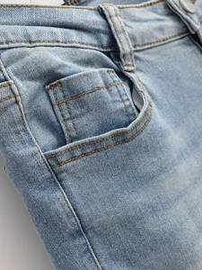 Gros plan d'un jean en denim délavé montrant les coutures de la poche et la texture