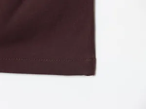 Nahaufnahme der feinen Nähte und des Saums an einem dunkelburgunderroten Kleid.