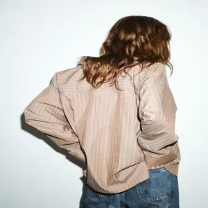 Vista posteriore che mostra la vestibilità di una camicia beige a righe con maniche ampie