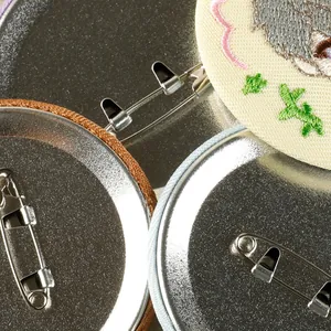 Macro detail of embroidered tinplate badges showing the safety pin back mechanism.