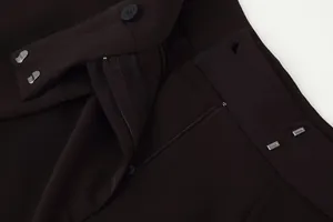 Close-up of waist detail on loose draping trousers with zipper and metal hook closure