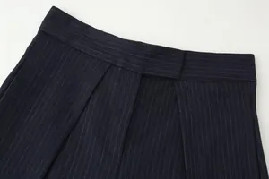 Close-up detail of high waist pinstripe trousers showing fabric texture and pleats