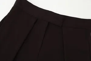 Close-up detail of high-waisted black wide-leg trousers showing waistband and pleats