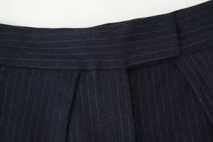 Close-up detail of navy pinstripe wide-leg trousers showing waistband and fabric texture