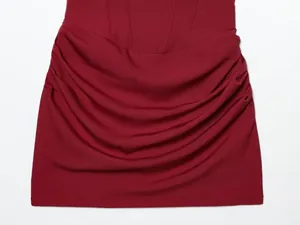 Nahaufnahme einer weinroten gerafften Bodycon-Kleid-Detail mit Stofftextur.
