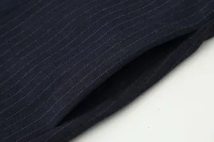 Macro view showing the side pocket and pinstripe texture of navy blue wide-leg pants.