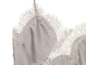 Detailopname van delicate wimperkant op een grijze satijnen camisole met luxe zijdeglans