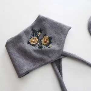 Detailed view of elegant floral bead embroidery on a gray knitted winter headband.