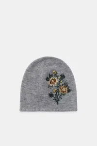 Close-up detail of gray knitted beanie with elegant floral embroidery and beads.