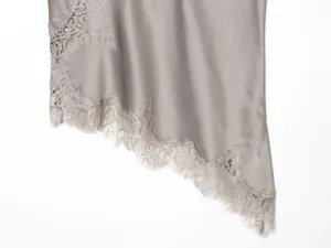 Detailopname van de verfijnde wimperkantzoom op een luxe grijze satijnen camisole top