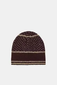 Detail shot of a dark brown knitted beanie hat with white polka dots and stripes.