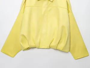 Primer plano de chaqueta bomber amarilla de ante que muestra el dobladillo y tejido