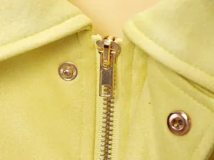 Detalle macro de una chaqueta bomber de ante amarillo con cremallera de metal dorado