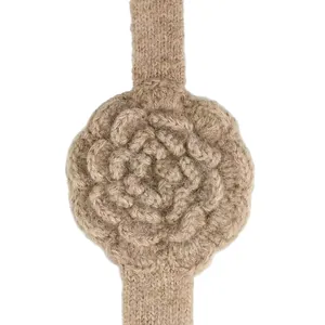 Close-up of a handmade knitted headband with a 3D crochet rose in tan wool material