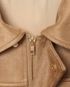 Primer plano detallado de una cremallera dorada en una chaqueta bomber de ante marrón de gala