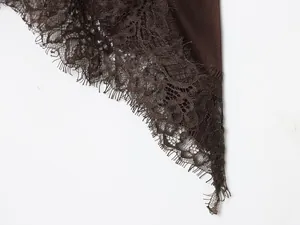 Detailopname van de delicate bruine kantafwerking op een satijnen hemdje met textuur
