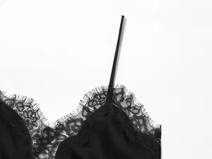 Gedetailleerde weergave van het fijne wimperkant op een zwarte satijnen top.