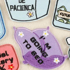 Diverse geborduurde patches met Engelse en Spaanse tekst en bloemmotieven op beige stof