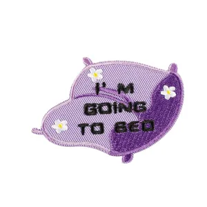 Paars kussen geborduurde patch met 'I'M GOING TO BED' tekst en bloemdetails