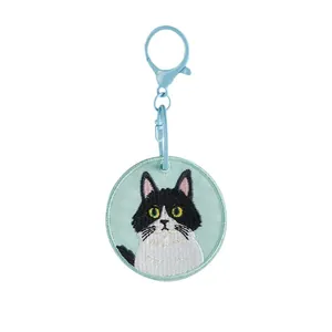 Cute embroidered tuxedo cat keychain on light blue round patch with matching clasp