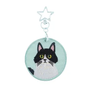 Gedetailleerde geborduurde tuxedo kat sleutelhanger met ster-vormige sluiting