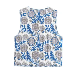 Detail view of a quilted floral vest with blue leaves and purple flowers on white.