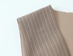 Macro view of vertical striped fabric and solid brown texture on a modern dress detail