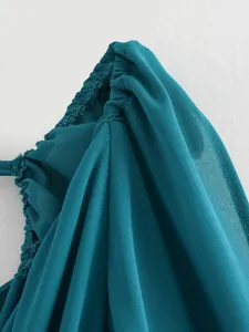 Détail de l'épaule d'une robe en mousseline sarcelle montrant des plis élégants
