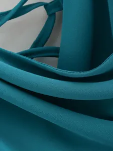 Détail macro d'un tissu texturé bleu sarcelle et de coutures fines d'une robe d'été