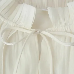 Dettaglio elegante vestito lungo bianco con un colletto a balze e fiocco delicato.