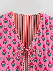Close-up of reversible quilted vest with pink floral pattern and striped lining detail