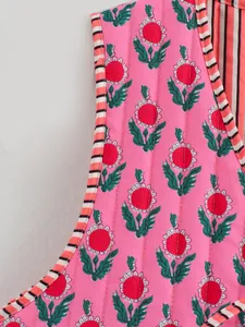 Close-up detail showing the vibrant floral pattern and quilted stitching on a pink vest