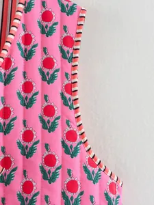 Close-up of pink floral quilted vest featuring vintage pattern and striped trim detail