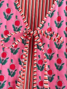 Detailed view of pink floral quilted reversible vest featuring a striped tie-front closure