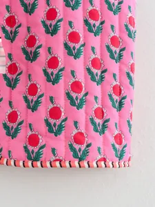 Detailed macro view of pink quilted cotton fabric with floral print and striped hem