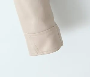 Détail rapproché de la manche d'une veste en similicuir crème avec coutures fines