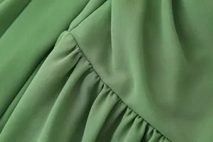 Gros plan détaillé du tissu de robe en mousseline verte montrant la texture plissée