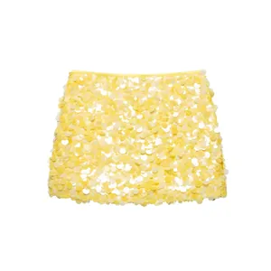 Detailansicht eines leuchtend gelben Pailletten-Minirocks mit schimmernder Textur