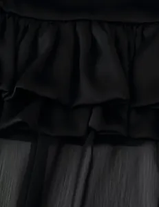 Macro view of multi-layered black ruffles and sheer chiffon fabric on a skirt.