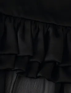 Close-up detail of tiered ruffles on a black long skirt with soft fabric texture