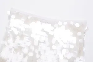 Detailaufnahme eines weißen Strick-Minirocks mit zarten floralen Pailletten-Verzierungen.