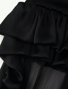 Close-up detail of a black multi-layered ruffled skirt with pleated fabric texture.