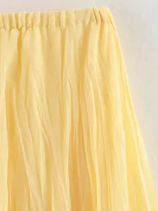 Détail d'une jupe midi plissée jaune montrant la taille élastique et la texture du tissu